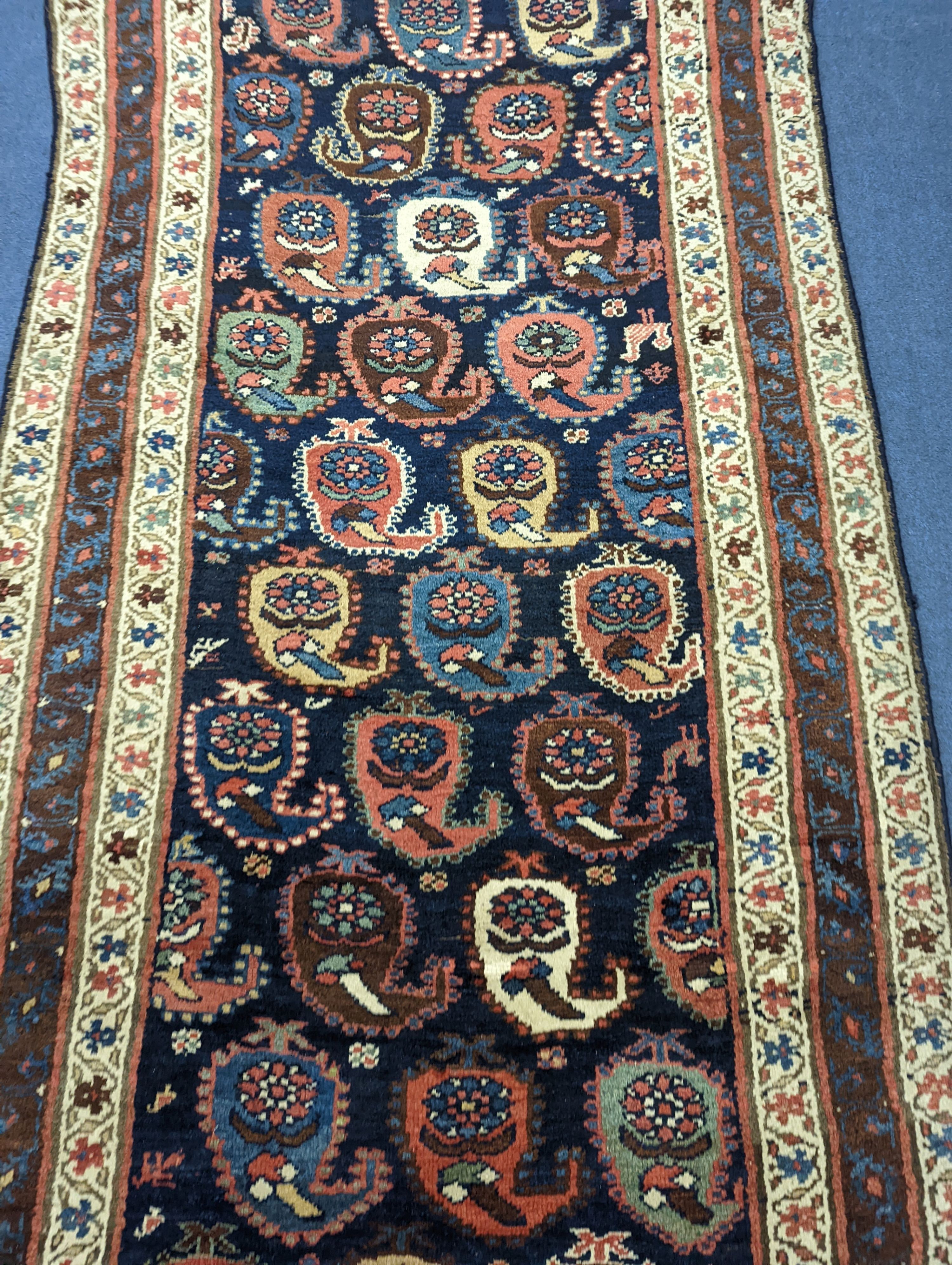 A Caucasian Karabagh blue ground runner, woven with rows of stylised boteh, figures and birds, 477 x 117cm